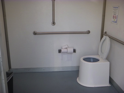 Accessible vault toilet in main parking lot – smooth surface – handrails on both walls – toilet paper dispenser